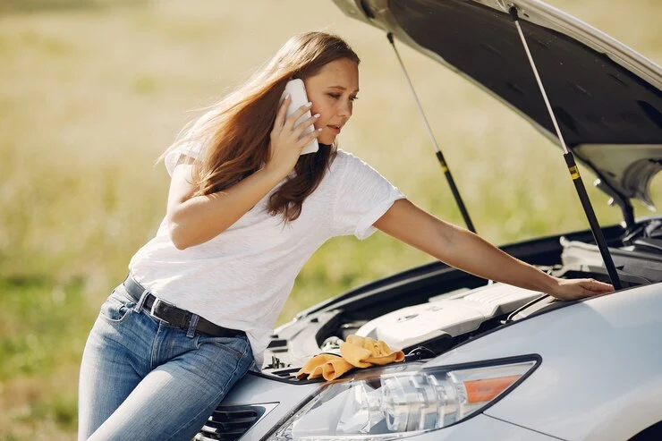 kvinne i nærheten av ødelagt bil ringer etter hjelp for vedlikehold av drivstoff
